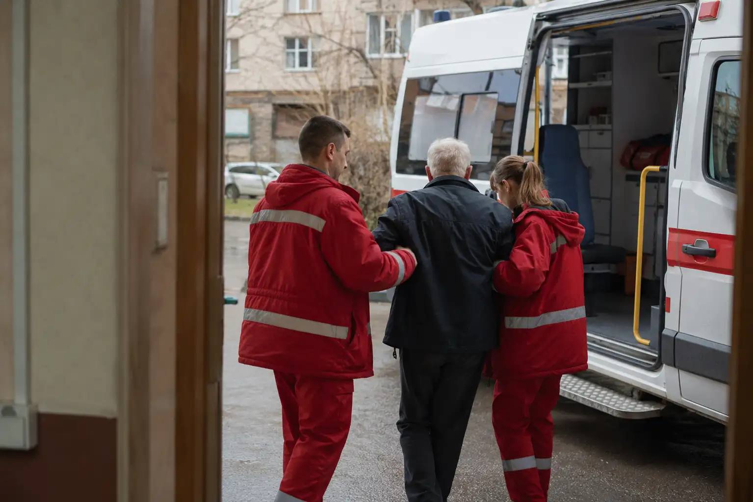 Врачи помогают больному пройти домой после выписки